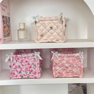 Close-up of quilted floral fabric storage baskets with blue bows on white shelves