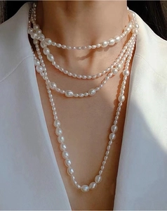 Close-up of layered baroque pearl necklace featuring different sizes of white pearls