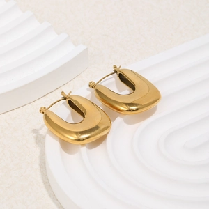Macro shot of 18K gold plated stainless steel U-shaped hoop earrings on a marble base