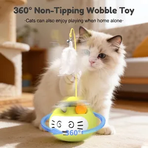 Yellow cat tumbler toy with feather wand and bell in a cozy home setting with a cat