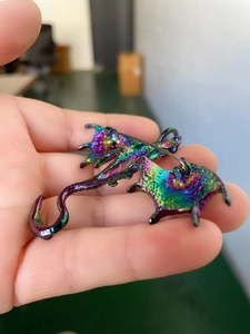 Detailed macro view showing the iridescent rainbow plating and metal pin back of dragon brooch