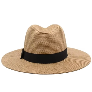 Close-up of a light brown woven straw fedora hat with a black satin ribbon band