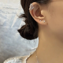 Detailed view of silver hollow butterfly ear cuff with intricate wing texture on model