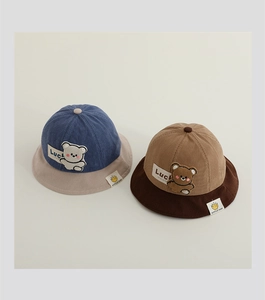 Detail of blue and brown corduroy baby sun hats featuring cute bear patches and Luck labels