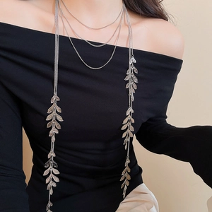 Detail of silver leaf layered tassel necklace on model with black off-shoulder top