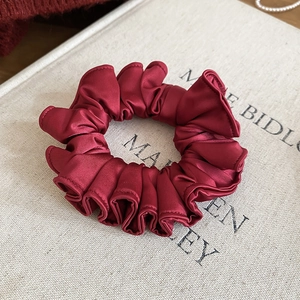 Detailed close-up of wine red satin pleated hair scrunchie with elegant ruffled texture