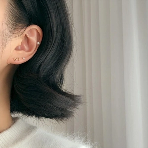 Close-up of model wearing 925 sterling silver bow and pearl stud earrings set in gold