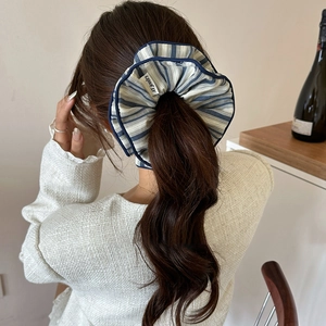 Elegant blue striped fabric scrunchie shown in a ponytail hairstyle for women