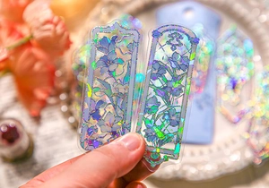 Detail of laser transparent PET bookmark with embossed gold floral pattern and rainbow effect