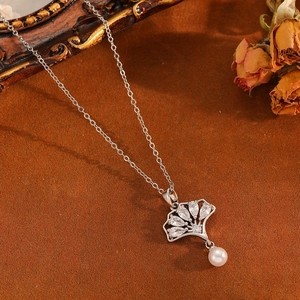 Détail du pendentif feuille de ginkgo argenté avec zircons brillants et perle blanche