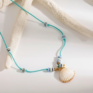 Detail of beach-style turquoise woven necklace with white shell pendant and beads
