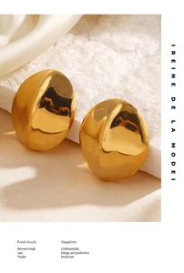 Detailed view of large gold organic curved earrings on white silk and crystals