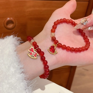 Détail d'un bracelet en perles d'agate rouge avec un pendentif cheval à bascule doré