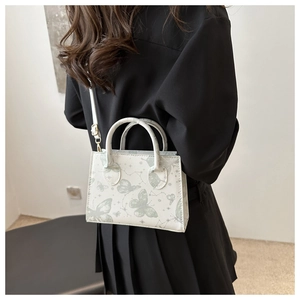 Detailed back view of white crossbody bag featuring green butterfly and star patterns