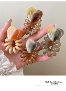Detail of four heart-shaped telephone wire hair ties in amber, brown, and cream colors