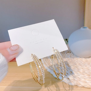 Detail of triple-layered gold hoop earrings with sparkling pave-set zircons on a card