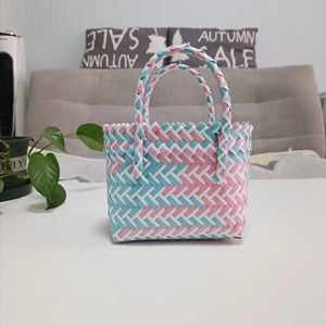 Detail of pink, blue and white woven handbag with zig-zag edge and double handles