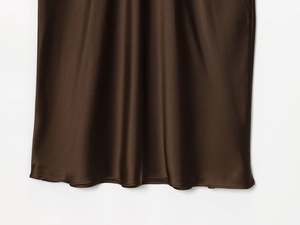 Close-up of dark brown satin fabric showing smooth texture and elegant drape on the skirt