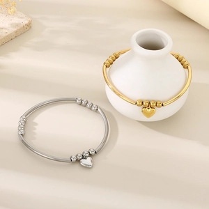 Détail de bracelets à billes en acier inoxydable avec pendentifs cœur en or et argent