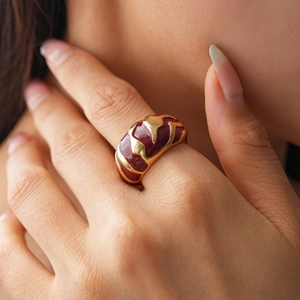 Macro view of a gold and burgundy enamel irregular geometric ring on a finger