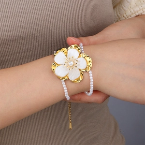 Close-up of a model wearing a gold shell flower and pearl bracelet with extender chain