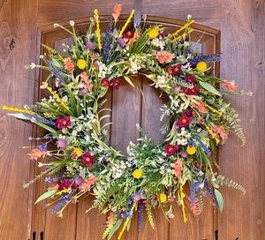 Dettaglio ghirlanda di fiori selvatici artificiali con foglie su porta di legno