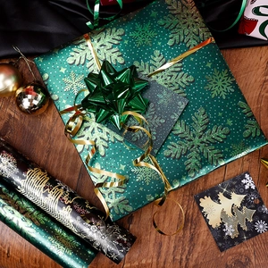 Christmas gift wrapping set with green snowflake paper, pink bows and gold ribbons