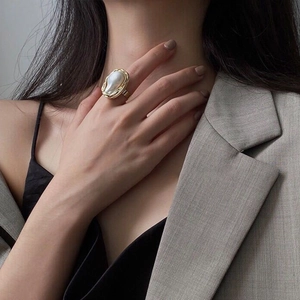 Detail of a large Baroque pearl ring with a textured gold setting on a model's hand
