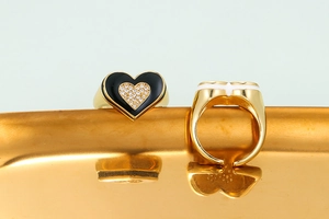 Detail of gold heart ring with black enamel outline and sparkling zircon inlay