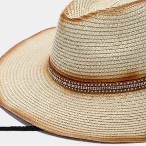 Detail of woven straw cowboy hat with leather band, rhinestones and rivets decoration
