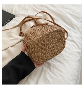 Detail of paper rope bucket bag featuring natural straw texture and brown leather strap