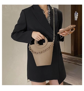 Detail of khaki bucket bag with circular handle and decorative thick chain strap