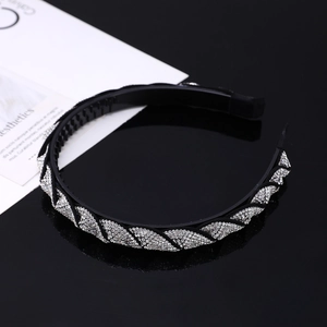 Detail of a black rhinestone headband showing anti-slip teeth and twisted diamond pattern