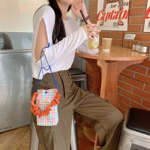 Close-up of a plaid crossbody bag with orange handle in a cozy industrial style cafe