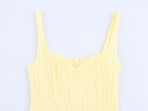 Detail of light yellow textured crepe fabric on a strap dress with a size S neck label