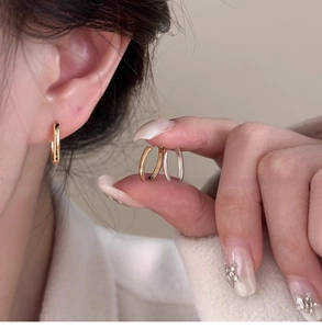 Dettaglio ravvicinato di orecchini a cerchio ovali in oro 18k e argento indossati sui lobi