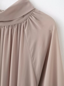Détails des plis froncés et du col montant sur ce chemisier en mousseline rose poudré