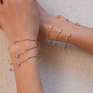 Gros plan de bracelets ouverts empilés en argent et or avec zircons étoiles et gouttes