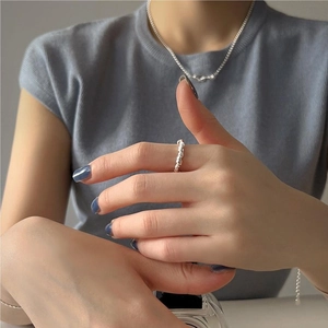Close-up of minimalist silver knot ring and matching necklace set on model