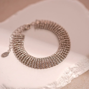 Close-up of a multi-row silver zircon bracelet with lobster clasp on a stone display
