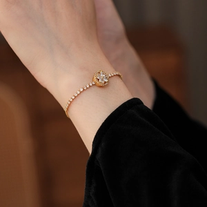 Macro shot of a sparkling zircon clover bracelet on a female wrist with black velvet sleeve
