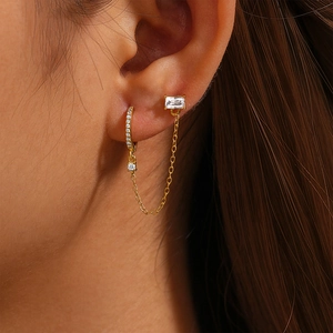 Macro shot of gold S925 sterling silver chain earrings with pavé heart and rectangular gems