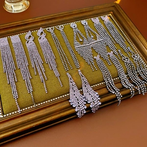 Vue détaillée de boucles d'oreilles à pompons argentés et strass sur présentoir de luxe