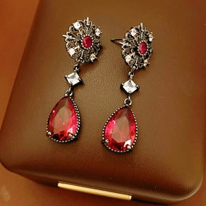 Détail de boucles d'oreilles vintage avec cristal rouge et zircone sur étui en cuir