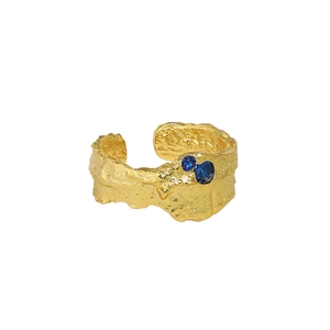 Irregular lava texture gold ring with blue zircon stones on white background