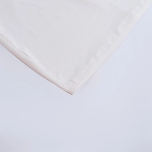 Detailed close-up of the double-stitched hem on a white knitted one-shoulder dress