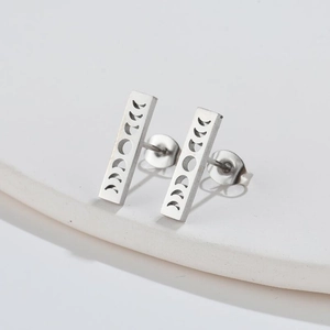 Detailed view of silver rectangular stud earrings with moon phase engraving on ceramic tray