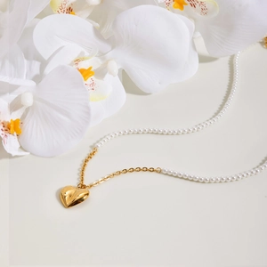 Elegant 18K gold heart pendant with white pearl beaded necklace on cream background