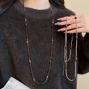 Close-up of bohemian tiger eye beaded necklace worn on a brown mohair sweater