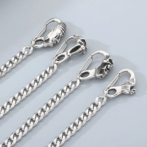 Macro detail of gothic skull and Buddha head charms on silver stainless steel pant chains